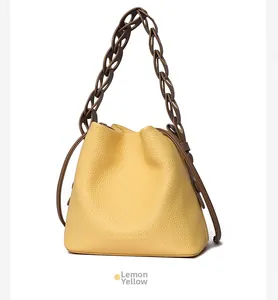 Detail of lemon yellow bucket bag featuring lychee grain leather and brown chain strap