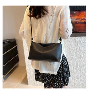 Close-up of black textured faux leather crossbody bag with minimalist vertical stitching
