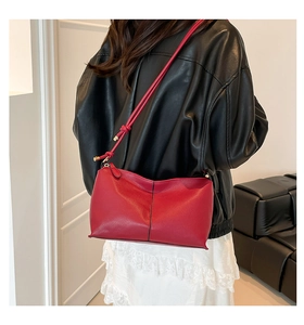 Detail of red matte leather shoulder bag with knot strap and black contrast stitching