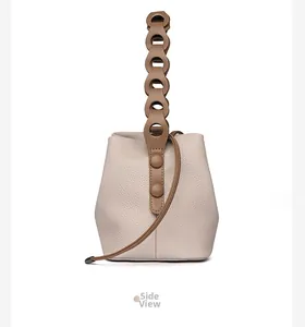 Side view of cream pebble leather bucket bag with brown circular chain handle detail