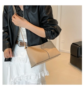 Detail view of beige crossbody bag with black contrast stitching and gold hardware