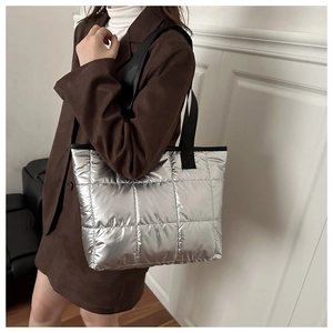 Close-up of silver quilted tote bag with black straps and large capacity detail