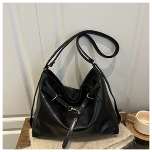 Detail of minimalist black PU leather tote bag with metallic buckle and slim strap