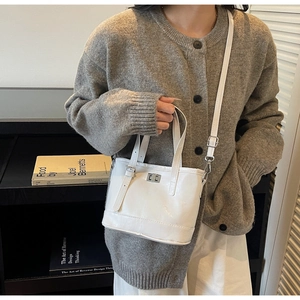 Détail du sac seau en cuir verni blanc avec fermoir rotatif argenté et bandoulière