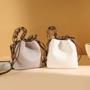 Minimalist leather bucket bag with hollow chain handle and drawstring closure