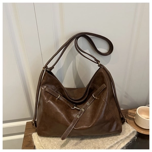 Detail of retro chocolate brown tote bag featuring decorative straps and metal buckles