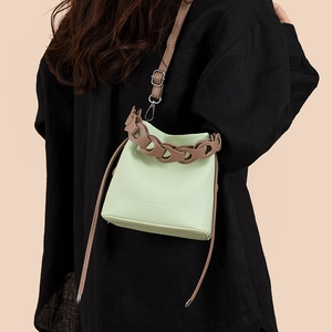 Pale green pebble leather bucket bag with brown chunky chain handle and shoulder strap
