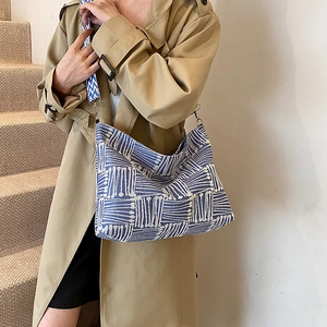 Striped knit shoulder bag with blue and white geometric patterns and a wide strap