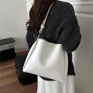 Minimalist white PU leather bucket bag with knotted shoulder strap detail on model