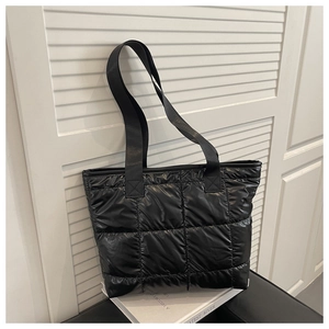 Detail of black quilted puffer tote bag made of high-gloss nylon with padded texture