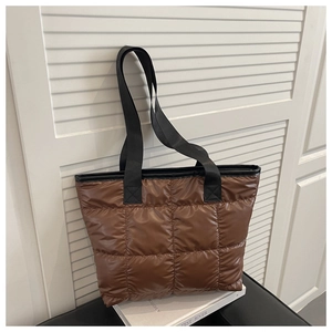 Detail of brown quilted tote bag showing large square stitching and black nylon straps