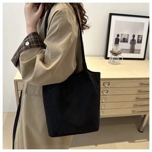 Minimalist matte black bucket bag styled as a shoulder tote for daily commute use