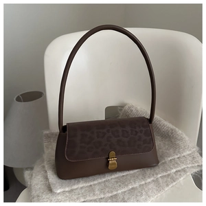 Détail du sac bandoulière léopard marron foncé avec boucle en laiton sur tricot