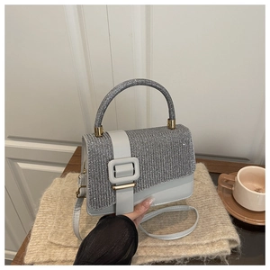 Detail einer silbernen Pailletten-Handtasche mit großer Schnalle und abnehmbarem Gurt