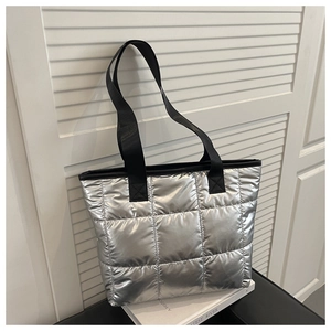 Macro shot of silver metallic quilted tote bag texture and durable black woven straps