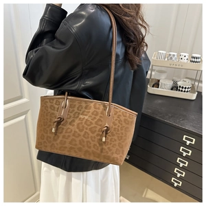Close-up of brown leopard print tote bag with leather straps and gold logo detail