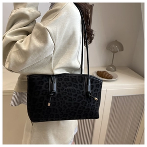Side view of the large leopard print shoulder bag worn by a model in a home setting