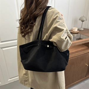 Borsa tote nera minimalista con fibbia in metallo e tracolla indossata da modella