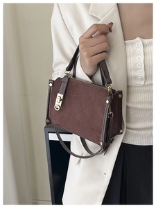 Detailed view of brown quilted box bag with golden clasp and adjustable strap