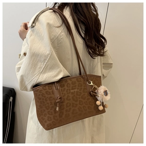 Macro detail of brown leopard print tote bag with plush charm and letter print