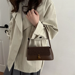 Sac baguette vintage marron avec rabat léopard et fermoir doré porté sous l'épaule