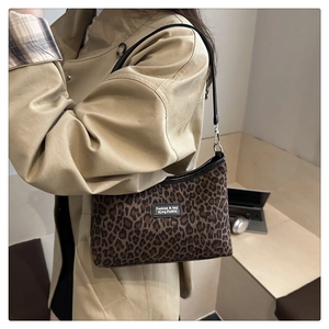Close-up of leopard print shoulder bag worn with a khaki coat in a minimalist lifestyle setting