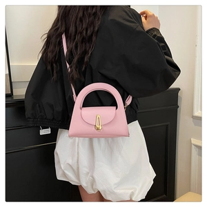 Detail of pink leather handbag with gold lock and semi-circular handle on model