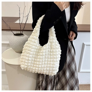 Close-up of beige popcorn texture shoulder bag with stylish pleated pattern and hobo style