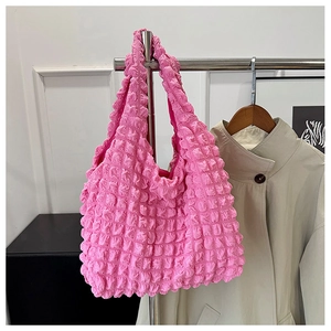 Detail of pink bubble texture fabric on a stylish shoulder tote bag hanging indoors