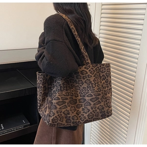 Détail du grand sac cabas à motif léopard porté à l'épaule dans un décor intérieur épuré
