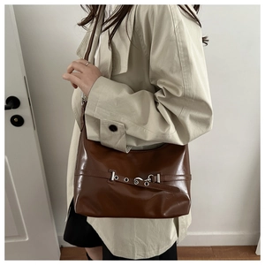 Vue détaillée d'un sac d'épaule marron brillant avec des boucles argentées élégantes