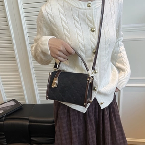 Quilted black square crossbody bag with brown leather handles and gold metal turn-lock