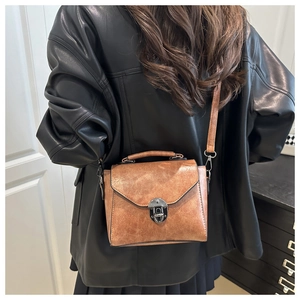 Sac bandoulière vintage marron caramel avec fermoir métallique porté par un mannequin