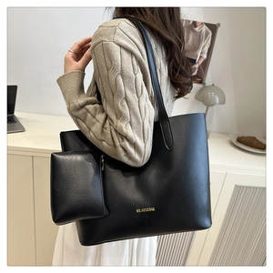 Close-up of black leather tote bag with matching zippered pouch and gold logo detail