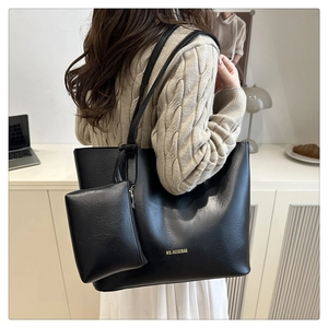 Close-up of black PU leather tote bag with gold logo and matching mini hanging pouch