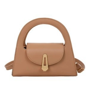 Minimalist tan leather handbag with round handle and gold geometric trapezoidal clasp