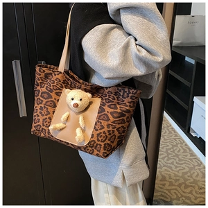 Leopard print tote bag detail showing plush teddy bear ornament and leather shoulder strap