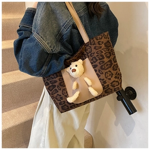 Close-up of leopard print tote bag featuring a cute plush bear on a beige front pocket