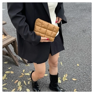 Chic brown quilted clutch bag with square pattern held by a model in autumn street style