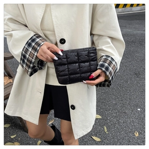 Detail of black quilted pouch showing shiny nylon texture and hand-held size scale