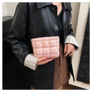 Detail showing the pink quilted puff clutch with soft texture held by a model