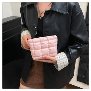 Detailed view of pink quilted handbag with square patterns held by a model in casual outfit