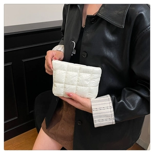 Close-up of a white quilted checkered handbag held by a model in a leather jacket