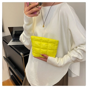 Macro view of bright yellow quilted nylon makeup bag texture and puffer design details