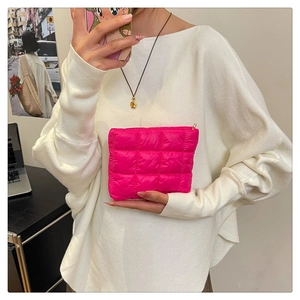 Detailed macro view of quilted puffer cosmetic bag in vibrant rose pink with gold zipper