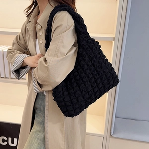 Minimalist black bubble textured tote bag with wide shoulder strap and elastic fabric