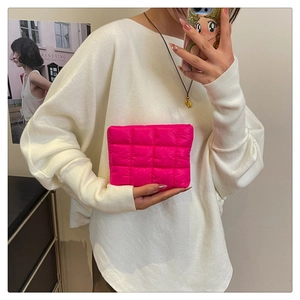 Detailed shot of quilted hot pink pouch made of soft padded material in model's hand
