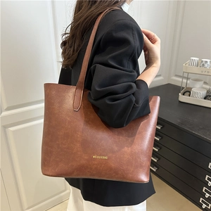 Vintage brown leather tote bag with shoulder strap worn by model in casual chic style