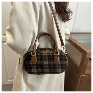 Detail der karierten Tweed-Kissentasche mit Ledergriffen und goldenen Metallhaken