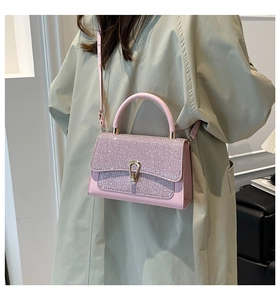 Close-up of pink leather handbag featuring a sparkling glitter flap and gold horseshoe lock